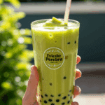 A person's hands holding a tall, refreshing glass of homemade Avocado Boba on a sunny day.