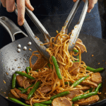Tossing the finished Thai Pork and Noodles together in a hot wok.