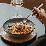 A person enjoying a quick and elegant weeknight dinner of Angel Hair with Sun-dried Tomatoes and Goat Cheese.