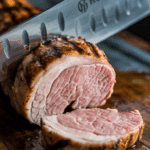 A knife slicing into the juicy, finished Grilled Pork Tenderloin.