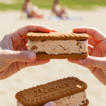 A hand holding a large, homemade Biscoff Ice Cream Sandwich on a sunny day.