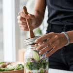 A person shaking a jar of the Winter Layered Salad to mix in the dressing.
