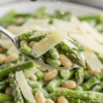 Garnishing the finished Parmesan Asparagus Salad with fresh shavings of Parmesan cheese.