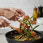 Tossing the finished Pork and Green Bean Stir-Fry in a skillet with a glossy glaze.