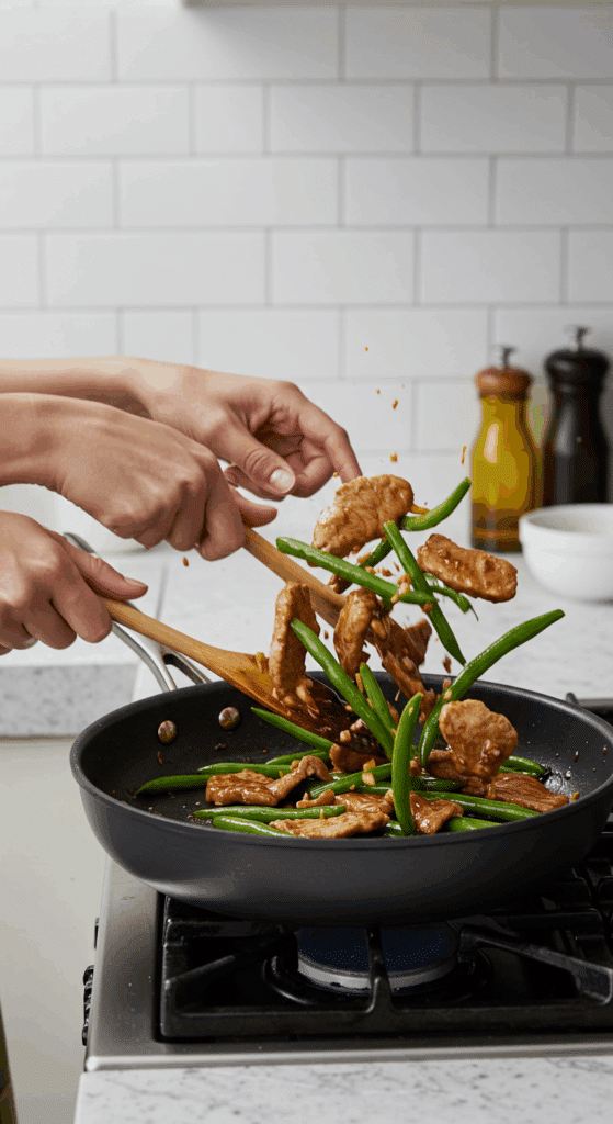 Tossing the finished Pork and Green Bean Stir-Fry in a skillet with a glossy glaze.