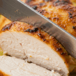 A knife slicing into the juicy, finished Thai Green Curry Chicken breast.