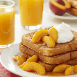 A beautiful plate of French toast topped with a generous serving of homemade Tipsy Peaches.