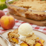 A perfect slice of warm homemade Old-Fashioned Peach Cobbler with a large scoop of melting vanilla ice cream.