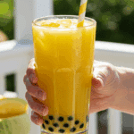 A person's hands holding a tall, refreshing glass of homemade Honeydew Bubble Tea on a sunny day.