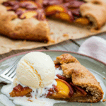 A perfect slice of warm, homemade Bourbon Pecan Peach Galette served with a large scoop of melting vanilla ice cream.