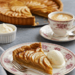 An elegant slice of French Apple Tart being served with a scoop of vanilla ice cream for dessert.