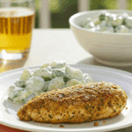 A beautiful plate of homemade, crispy Falafel-Crusted Chicken served with a fresh cucumber salad for a healthy lunch.