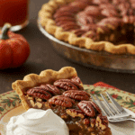 A perfect slice of homemade Pecan Pie with a dollop of whipped cream being served for a holiday dessert.