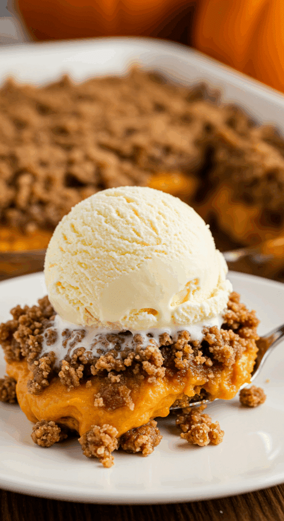 A warm, cozy bowl of homemade Pumpkin Dump Cake with a large scoop of melting vanilla ice cream on top.