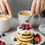 A person enjoying a healthy breakfast of High-Protein Cottage Cheese Pancakes with fresh berries and yogurt.