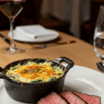 An elegant, individual serving of Spinach Gratin on a plate next to a perfectly cooked steak.