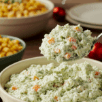 A delicious scoop of homemade Watergate Salad being served from a bowl at a happy family potluck.