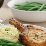 An elegant plate of homemade, pan-seared Honey-Garlic Pork Chops, served with mashed potatoes and green beans for a healthy meal.