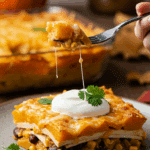 A beautiful plate of homemade, cheesy Butternut Squash Casserole topped with sour cream, being served for a cozy fall family dinner.