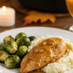 A classic dinner plate with a serving of homemade, saucy Apple Cider Chicken, served with mashed potatoes and Brussels sprouts.
