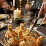The finished, puffed-up Salmon in Parchment packets being served at a sophisticated and elegant dinner party.