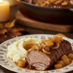 An elegant plate of homemade, tender Apple Cider Braised Pork Shoulder with a rich gravy, served with mashed potatoes for a cozy meal.