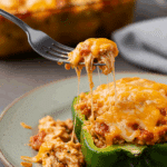 A beautiful, cheesy, homemade Chicken Stuffed Pepper being served for a casual family dinner.