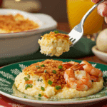 A beautiful plate of a homemade, elegant, and creamy Garlic Grits Casserole, being served with a few large, sautéed shrimp at a holiday brunch.