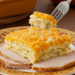 A beautiful plate of a homemade, elegant, and crispy Scalloped Potato Gratin, being served with a thick slice of a roasted turkey at a Thanksgiving dinner.