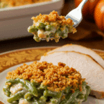 A beautiful plate of a homemade, elegant, and crispy-topped Green Bean Casserole, being served with a thick slice of a roasted turkey at a Thanksgiving dinner.