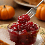 A beautiful plate with a homemade, elegant, and chunky Cranberry-Orange Sauce, being served with a thick slice of a roasted turkey at a Thanksgiving dinner.