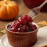 A beautiful plate with a homemade, elegant, and chunky Cranberry Sauce, being served with a thick slice of a roasted turkey at a Thanksgiving dinner.