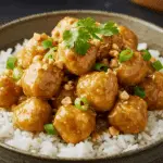 A beautiful, rustic bowl of homemade, easy, and creamy Peanut Chicken, with a glossy, light brown peanut sauce, served over a bed of fluffy rice and garnished with cilantro.
