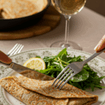A beautiful plate of a homemade, elegant, and savory Buckwheat Crepe, being served with a simple green salad at a brunch party.
