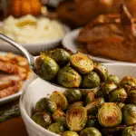 A beautiful bowl of homemade, crispy Roasted Brussels Sprouts being served as a side dish at a festive Thanksgiving holiday dinner.
