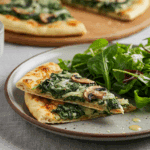 A beautiful plate of homemade, crispy and cheesy Spinach and Mushroom Naan Pizza being served for a casual family dinner.