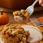A beautiful plate of a homemade, elegant, and crispy-topped Stuffed Mushroom Stuffing, being served with a thick slice of a roasted turkey at a Thanksgiving dinner.
