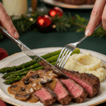 A beautiful plate of a homemade, elegant, and sliced Pan-Seared Rib-Eye, being served with a rich mushroom sauce, mashed potatoes, and roasted asparagus at a holiday dinner.